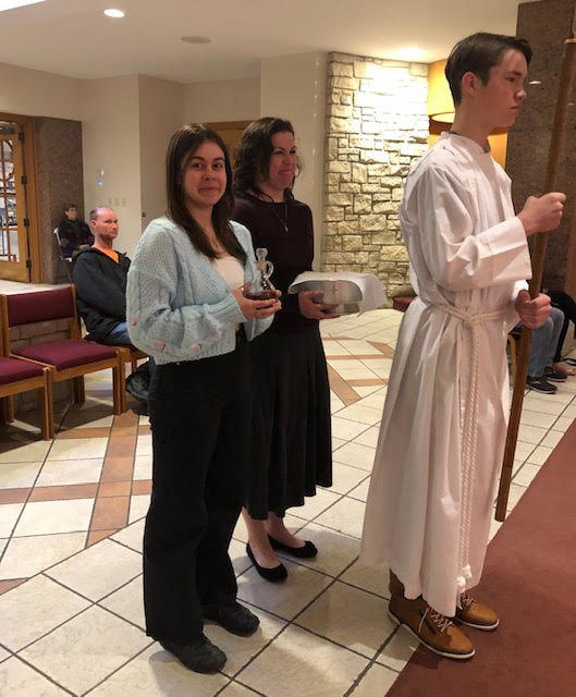 Judith Giger’s godmother, Karolina, left, prepares to take part in the Offertory Procession during the Mass of the Lord’s Supper on Holy Thursday in Our Lady of Lourdes Church in Columbia. Karolina, an exchange student from Poland, invited Ms. Giger to start going to Mass with her. Ms. Giger decided to become Catholic through the Rite of Christian Initiation of Adults.